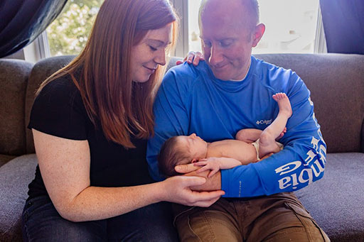 Ashley and Bill with baby Maddie on couch