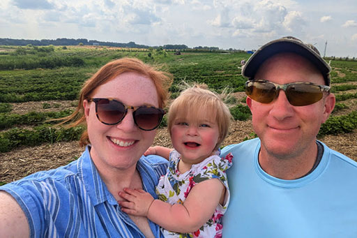 Ashley and Bill with Maddie in field of strawberries